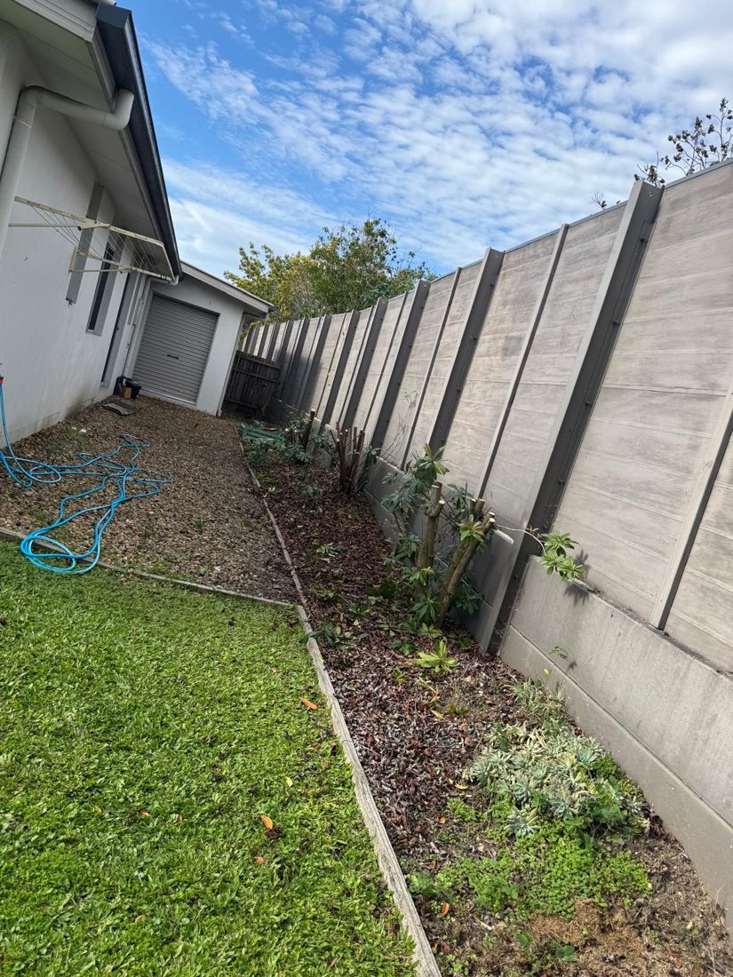 Cleared garden bed beside a Brisbane home after tree and shrub removal